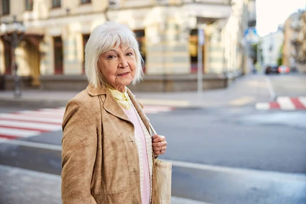 Kobieta w średnim wieku przechodzi przez miasto i uśmiecha się — Zdjęcie stockowe
