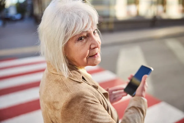 Powrót widok starsza kobieta gospodarstwa mobilne w jej rękach — Zdjęcie stockowe