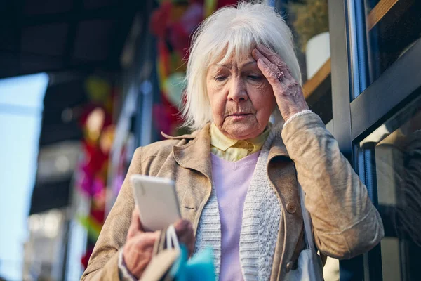 Idős nő olvas valamit a képernyőn mobiltelefon — Stock Fotó