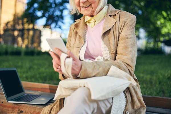 Idős nő, a modern eszközeivel a szabadban. — Stock Fotó