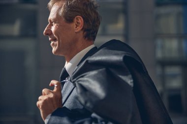 Takım elbiseli neşeli iş adamı sokakta dikiliyor.