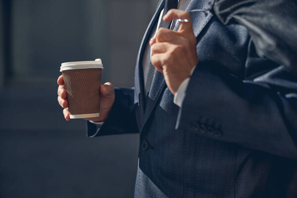 Male hand holding takeaway cup of coffee