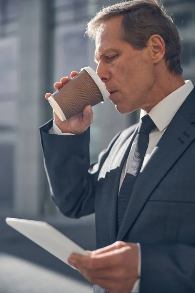 Schöner Mann trinkt Kaffee und nutzt Tablet-Computer im Freien — Stockfoto