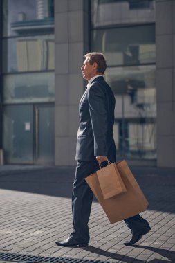 Sokakta yürüyen takım elbiseli yakışıklı bir adam.