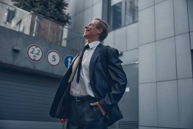 Sokakta duran takım elbiseli, gülümseyen adam.