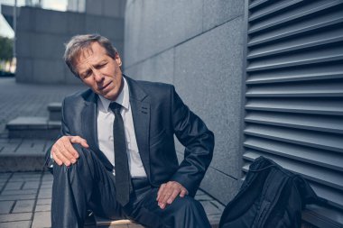 Dışarıda oturan yorgun ve mutsuz bir adam.