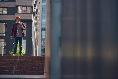 Neşeli stil sahibi adam sokak merdivenlerinde dikiliyor.