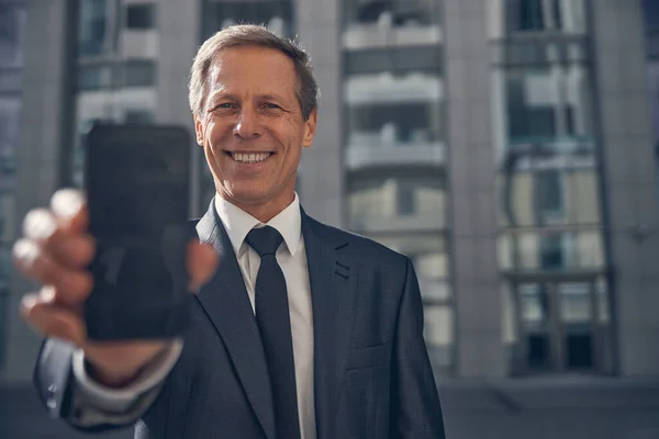通りにスマートフォンが立っている陽気なビジネスマン — ストック写真