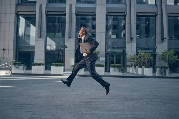 Hombre alegre hablando por celular y corriendo rápido en la calle —  Fotos de Stock