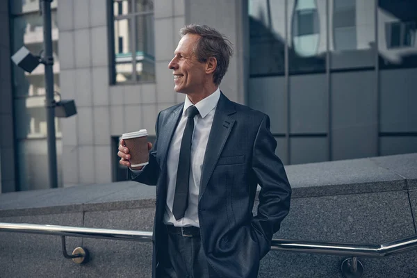 Radostný podnikatel pije kávu na ulici — Stock fotografie