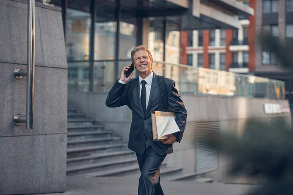 Веселый бизнесмен разговаривает по мобильному телефону на открытом воздухе — стоковое фото