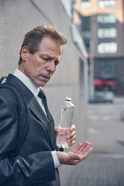 Stilig man i kostym håller piller och flaska vatten — Stockfoto