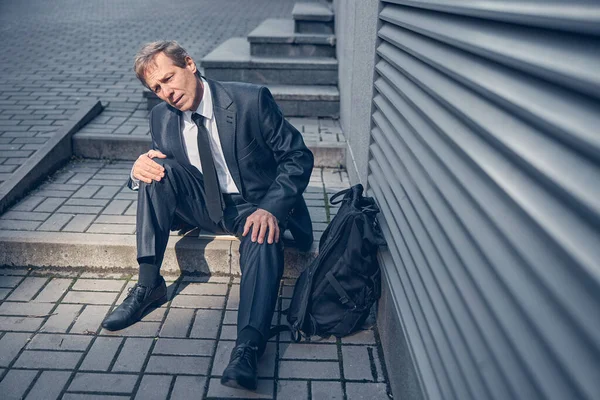 Homme fatigué assis sur les marches de la rue — Photo