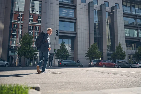 Uomo allegro con zaino che cammina per strada — Foto Stock
