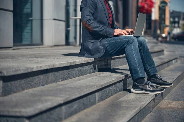 Стильный мужчина с современным ноутбуком на улице — стоковое фото