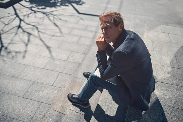 Красивый мужчина сидит на ступеньках на улице — стоковое фото