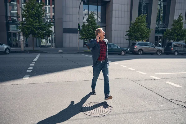 Веселый мужчина разговаривает по мобильному телефону и ходит по улице — стоковое фото