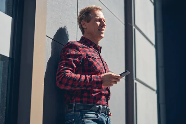 Красивый радостный человек, использующий смартфон на открытом воздухе в солнечный день — стоковое фото