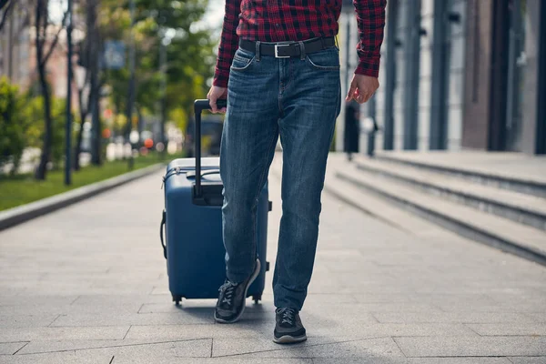 Стильный мужчина с дорожным чемоданом ходит по улице — стоковое фото