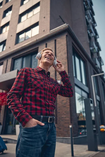 Uomo gioioso in cuffie wireless ascoltare musica all'aperto — Foto Stock