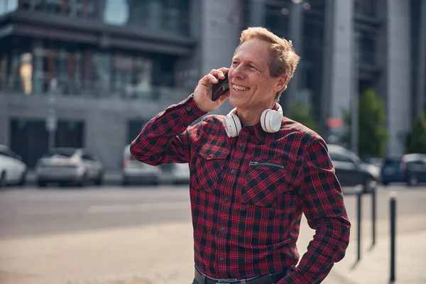 Красивый радостный мужчина разговаривает по мобильному телефону на улице — стоковое фото