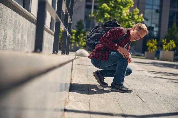 Stylish man suffering from knee pain outdoors — Stock Photo, Image