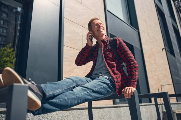 Hombre alegre y guapo hablando en el teléfono celular al aire libre —  Fotos de Stock