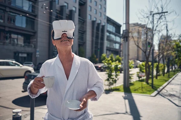 Allegro uomo in accappatoio utilizzando VR auricolare all'aperto — Foto Stock