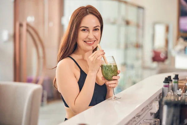 Sonriente hermosa mujer bebiendo un batido verde —  Fotos de Stock