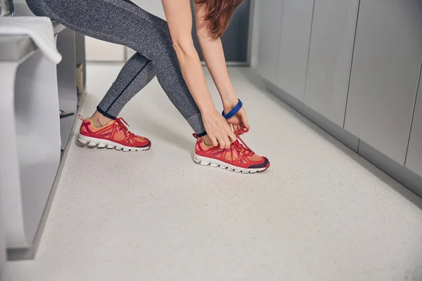 Junge, fitte dunkelhaarige Kaukasierin, die Schnürsenkel bindet — Stockfoto