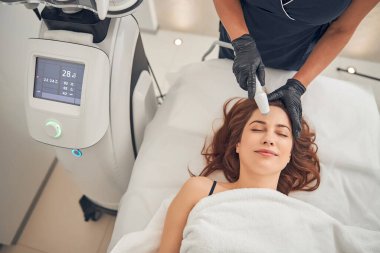 Güzellik uzmanı bir kadının yüzündeki kırışıklıkları gideriyor.