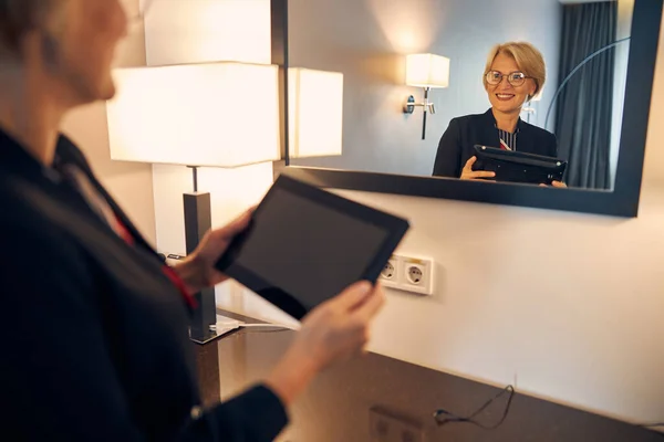 Mujer alegre usando tableta en la habitación del hotel —  Fotos de Stock