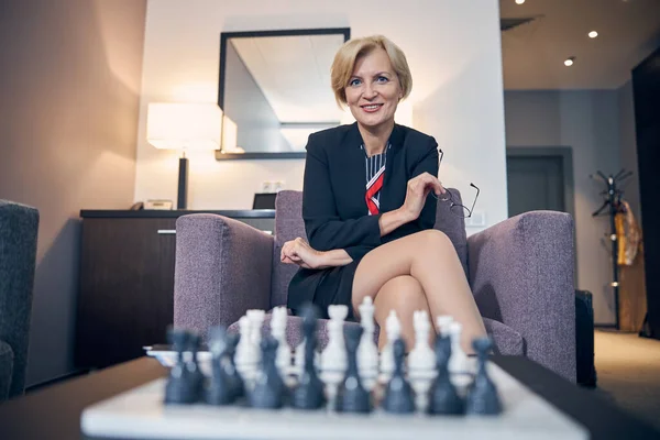 Cheerful businesswoman sitting in armchair in hotel room — Stock Photo, Image