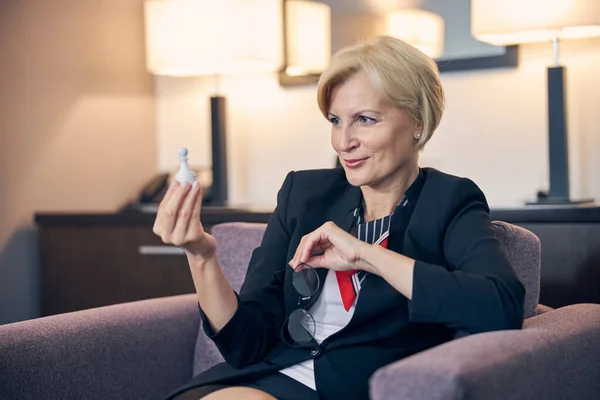 Beautiful businesswoman holding white chess pawn and glasses — Stock Photo, Image