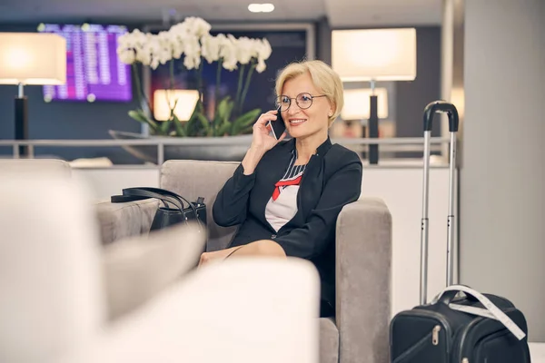 Charmante Frau telefoniert während des Wartens auf einen Flug — Stockfoto