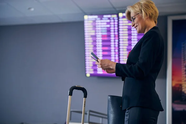 Çekici sarışın kadın biletleri kontrol ediyor ve havaalanında. — Stok fotoğraf