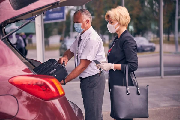 Aeropuerto trabajador masculino ayudar a la señora a poner el equipaje en el maletero — Foto de Stock