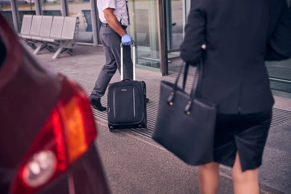 Luchthaven mannelijke werknemer helpen zakenvrouw om bagage te dragen — Stockfoto