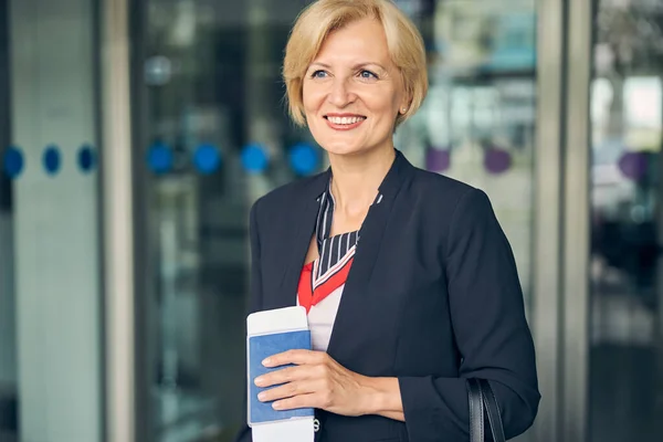 Cheerful female traveler standing outside airport terminal — Stock Photo, Image