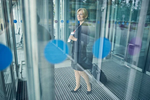 Encantadora mujer de pie detrás de vidrio en la terminal del aeropuerto —  Fotos de Stock