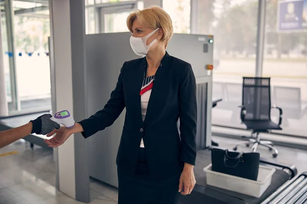 Guardia de seguridad del aeropuerto midiendo la temperatura de la señora antes del vuelo — Foto de Stock