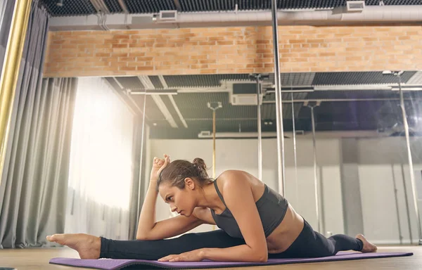 Sportliche junge Frau dehnt sich im Pole Dance Studio — Stockfoto