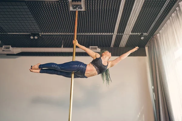 Beautiful young woman demonstrating her pole dance skills