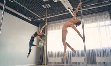 İki güzel genç kadın direk dansı yapıyor.