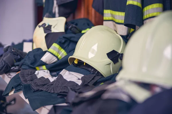 Fatos de bombeiro e capacetes pendurados no quartel de bombeiros — Fotografia de Stock