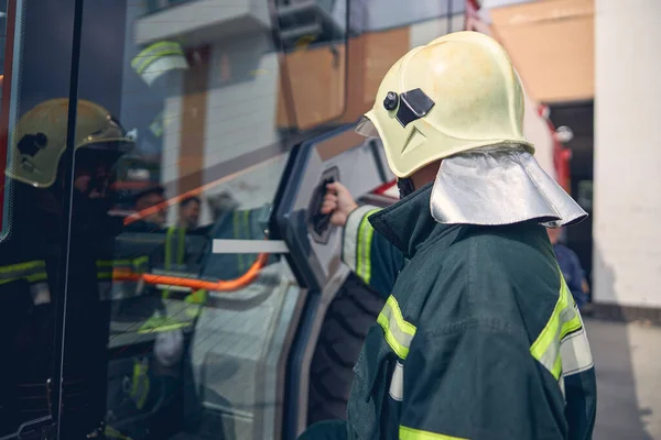 Volwassen brandweerman brengt tijd door in de buurt van de moderne truck voor noodgevallen — Stockfoto