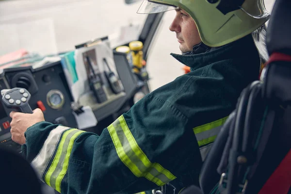 Gammal man tittar framåt medan han sitter i brandmaskinen — Stockfoto