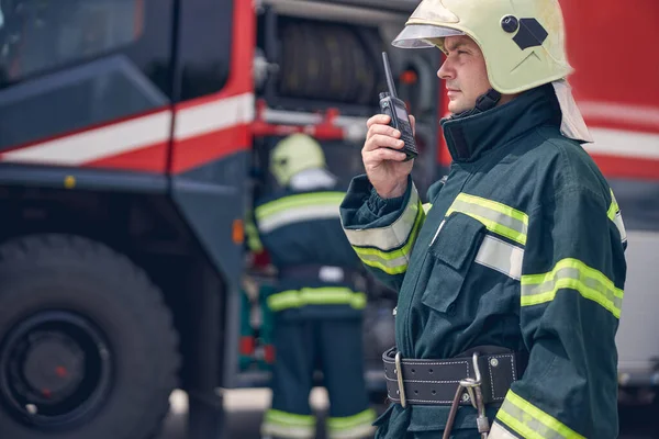 Man bär hjälm och skyddande uniform håller walkie i handen — Stockfoto