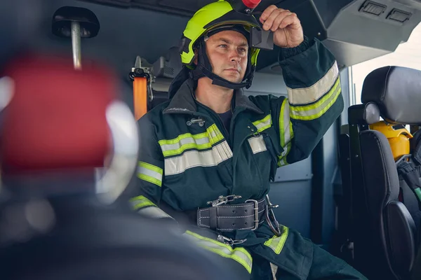 Man met groen beschermend uniform en helm in de machine — Stockfoto