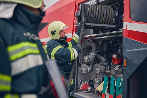 Brandman med säker hjälm bredvid brandbilen — Stockfoto